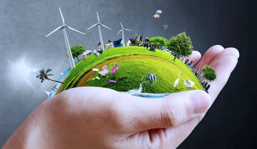 A hand holding a globe with wind mills and trees.